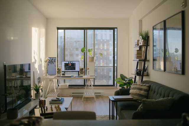 interior view of an apartment containing a black leather sofa near glass windows